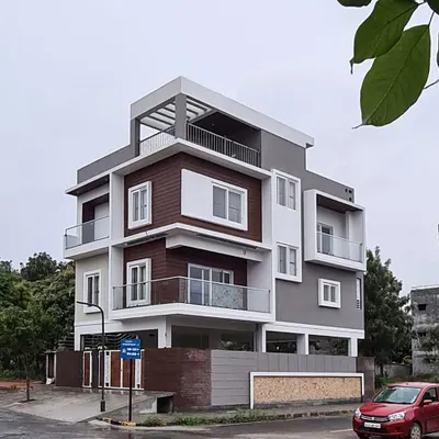 A completed residence at Bluejay Atmosphere, showcasing a clean, modern aesthetic. The design uses a balanced composition of white, grey, and wood-textured panels to define the elevation of this corner plot home.