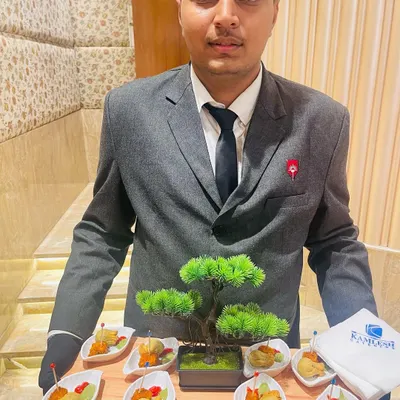 Our well-dressed staff presenting a tray of appetizers. The presentation, featuring a miniature bonsai tree, reflects our attention to detail and commitment to enhancing the overall dining experience.