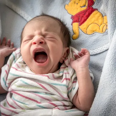 For this newborn portrait, the focus was on creating a safe and comfortable environment. The baby's natural, sleepy yawn against a soft, character-themed blanket makes for a heartwarming and authentic photograph you will treasure.