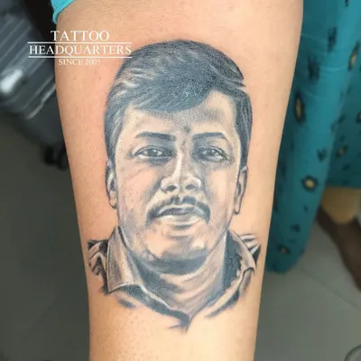 A realistic portrait tattoo capturing a gentle and warm expression. Our black and grey work focuses on soft shading to bring the image to life.