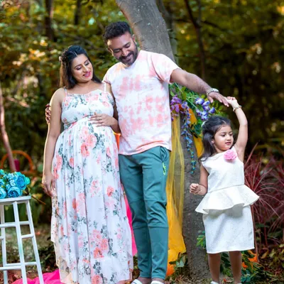 A candid moment from a full family maternity shoot outdoors. The older sister's playful dance brings a wonderful energy to the portrait, showing the happy and relaxed atmosphere of our sessions.