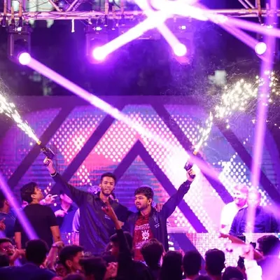The main stage of a college fest comes alive with performers, pyrotechnics, and laser lights.