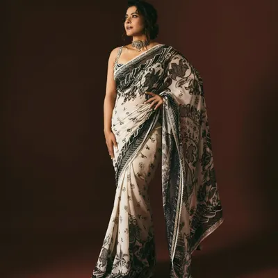 A full-length view of Kajol in a stunning black and white summer print saree. The look is paired with a statement choker, creating a style that feels like a piece of art from a gallery.
