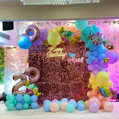 A vibrant candy-themed 2nd birthday party at a banquet hall. We used a colorful pastel balloon arch, a sparkling shimmer wall, and custom neon signs to create a magical atmosphere for the little one.