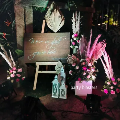 A warm welcome for your guests sets the tone for the event. This rustic wooden sign is paired with bohemian-style dried palms, fresh pink roses, and lanterns to create a chic and inviting entrance.