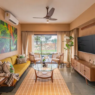 The living room of the Earth Villa, where lime-plastered walls create a warm, textured envelope. I selected mid-century modern furniture in natural wood and cane to complement the earthy aesthetic, while the large window frames a view of the surrounding landscape.