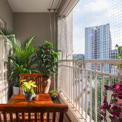 This balcony view shows how even with a safety net, a green and pleasant space can be created. The plants are positioned to thrive while offering a beautiful view of the city beyond.
