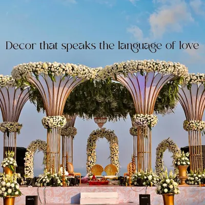 This grand mandap, set against the open sky, is one of my signature destination wedding designs. The structure features large, trumpet-like pillars topped with dense white chrysanthemums and filled with lush greenery, creating a breathtaking focal point for the ceremony.
