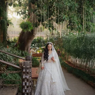 A beautiful shot of the bride walking along a garden path, her veil trailing behind her, creating a sense of movement and grace.