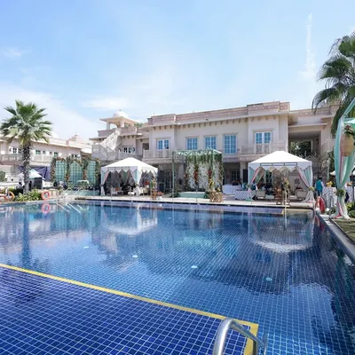 A wide shot of a "Tropical Oasis" themed poolside event, featuring canopies, lounge seating, and a fresh, vibrant color palette.