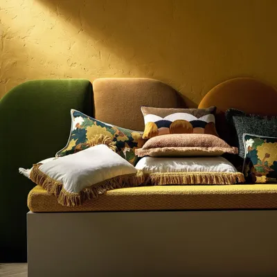A plush arrangement of cushions from the Fall Winter 2024 Accessories Collection. This assortment showcases a rich blend of textures, from fringed linens to patterned jacquards and abstract velvets, demonstrating our artful approach to creating layered, comfortable, and visually stimulating accents.
