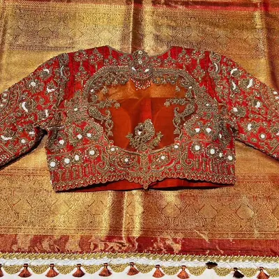 This bridal blouse, crafted in rich red raw silk, is fit for royalty. The design features exquisite hand embroidery with pearl and zardozi work around a sheer organza panel, creating a look of pure opulence.