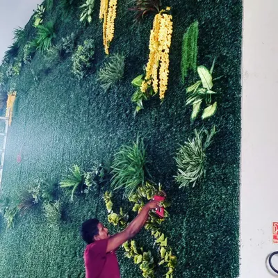 Here is a member of my hard-working team carefully installing an artificial green wall. We take great pride in our work, ensuring every piece is securely fitted to create a flawless and lasting final result.