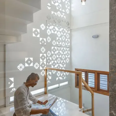 The play of light and shadow through a custom-designed jali screen creates a dynamic, shifting pattern on the wall of this staircase, turning a simple surface into a piece of art.