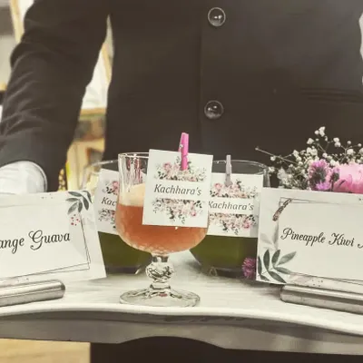 Impeccable service extends to our beverage offerings. Here, a member of my team presents freshly made juices, including Orange Guava and Pineapple Kiwi Mint, with personalized labels for the event.