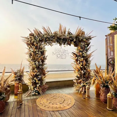 This is the full view of a boho-themed proposal I set up at Grey Goose, right by the sea. The floral arch, pampas grass, and jute rugs create a perfect romantic pathway for the big question.