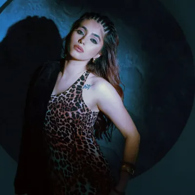A moody shot from a fashion editorial, using a single spotlight against a dark background. This dramatic lighting creates a cinematic feel, perfect for showcasing the bold leopard print dress.