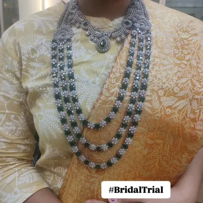 A client trying on our layered diamond and emerald look-alike necklace during a bridal trial. This helps visualize how the jewellery will look with her skin tone and outfit.