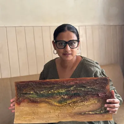 Here I am, sitting with one of my favorite textured art series. This piece features a rich, earthy palette and a landscape-like feel, created on paper.