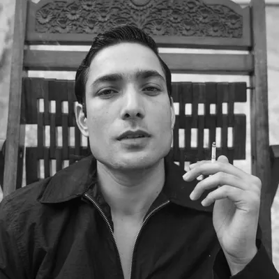 A classic, cinematic black and white portrait for a male actor. The direct gaze and the prop create a strong sense of character and story.