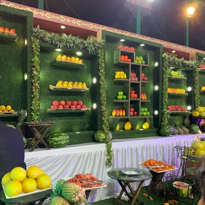 I believe food presentation should be as beautiful as the decor. Here is a creative fruit salad corner I designed, with fruits displayed artfully on shelves against a greenery wall.