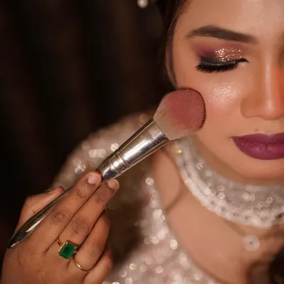The final dusting of blush to add a healthy, rosy glow. This close-up shows the flawless texture of the skin and the beautiful shimmer on the eyes.