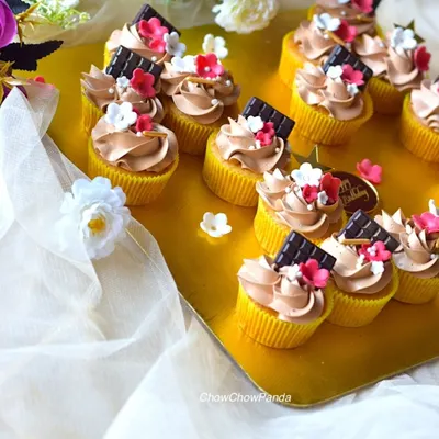 A set of my popular choco-vanilla cupcakes. I've topped the chocolate frosting with a small piece of dark chocolate and tiny, delicate sugar flowers for an elegant look.