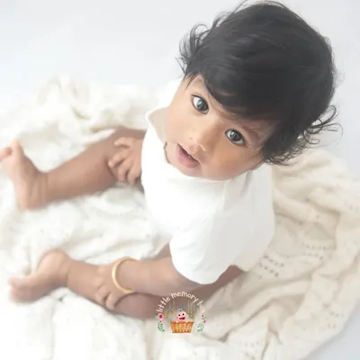 This is the essence of my minimalist style. A beautiful baby on a simple, soft white blanket. The focus is entirely on their innocent expression and bright eyes.