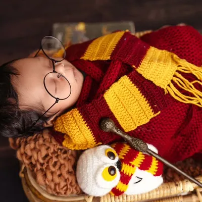 Welcome to Hogwarts. A sleeping newborn transformed into a tiny Harry Potter, safely swaddled in a Gryffindor-colored wrap and complete with iconic glasses and a magic wand.