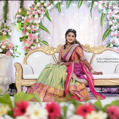 A doll-like look for a traditional half-saree ceremony. The vibrant colors of the outfit are matched with fresh, youthful makeup, making it a memorable day for the young lady.