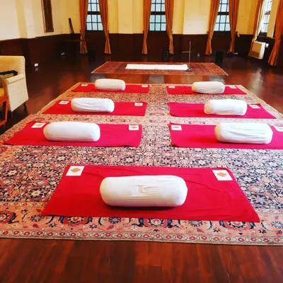 A yoga space prepared for a session, with mats and bolsters ready. The beauty of yoga is that it is for everyone, regardless of age or fitness level. It is a practice that calms the mind and strengthens the body.