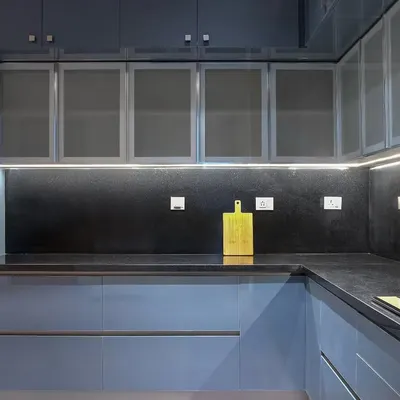 The combination of glossy blue cabinets and a dark, reflective backsplash creates a sleek and moody atmosphere. The under-cabinet lighting is essential here, highlighting the workspace and adding a beautiful glow that bounces off the surfaces.