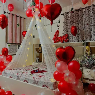 A complete romantic room decoration for a birthday or anniversary surprise. I used a canopy with fairy lights over the bed, red heart-shaped balloons, and loose balloons on the ceiling and floor.