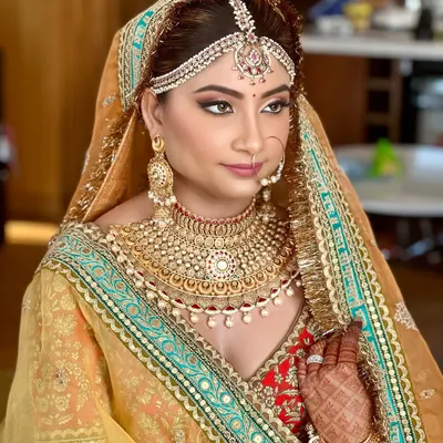 A regal bridal portrait featuring a classic Sabyasachi lehenga. The makeup was designed to be timeless, with bold eyes and glowing skin to complement the intricate gold jewelry and rich mustard tones of the outfit.