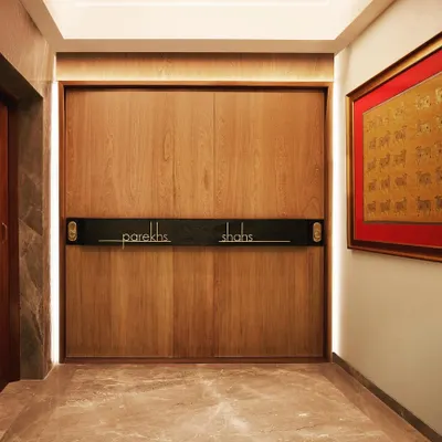 We transformed a single large apartment into two distinct homes for related families, starting with this shared entrance that uses a sliding wooden door to cleverly designate the two residences.