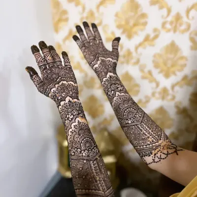 A beautiful example of full-coverage engagement henna, featuring geometric patterns and traditional motifs extending up the forearm.