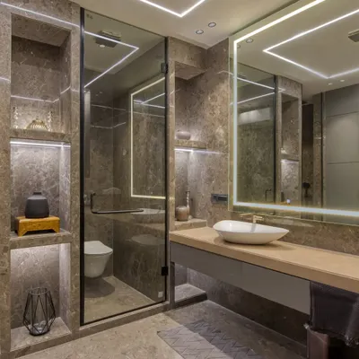 This modern bathroom is a showcase of integrated lighting and luxurious materials. We used marble-clad walls with built-in, illuminated niches for storage and display, creating a warm and functional space.