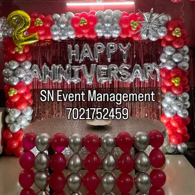 Here is a vibrant setup for a 2nd anniversary party. We used a bold red and silver theme to create a rectangular balloon arch and a decorative front for the cake table. The large "HAPPY ANNIVERSARY" foil letters stand out against the red foil curtain.