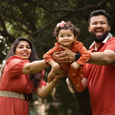 Pure, unadulterated joy. This family portrait in a beautiful garden setting captures a moment of fun and flight, with the parents lifting their little girl up in laughter.