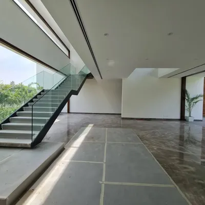 An in-progress photograph from one of our farmhouse sites. This image reveals the home's strong architectural bones, including the clean lines of the modern staircase with its glass railing, the expansive window openings, and the beautiful grey marble flooring being installed.