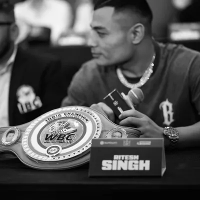 From dreams to the belt. A black and white shot of our fighter Ritesh Singh with his hard-earned WBC India Champion belt at a press conference.