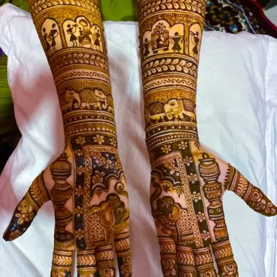 A bridal theme design telling a story on the arms. This mehendi features figures from a wedding procession, including elephants and doli scenes, making it a truly unique piece of art.