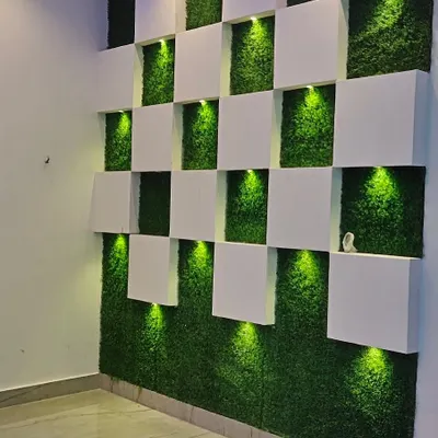 A modern and creative artificial green wall design. The combination of the grass texture with 3D panels and accent lighting creates a unique and stylish feature.