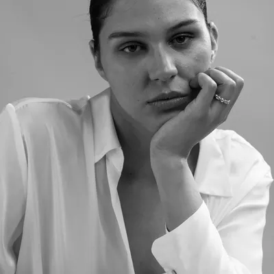 A raw and intimate black and white portrait. The minimal styling and close framing create a powerful sense of connection, focusing entirely on the subject's contemplative expression.