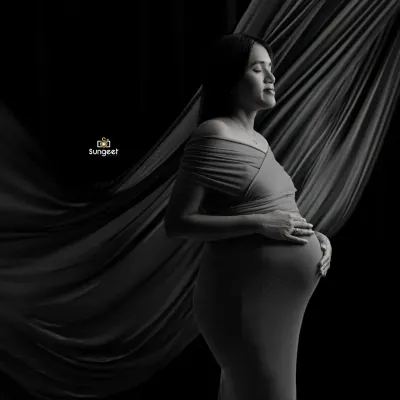 A dramatic and artistic black and white portrait. We used flowing fabric and directional light to sculpt the scene and create a powerful, emotional image of the mother-to-be.
