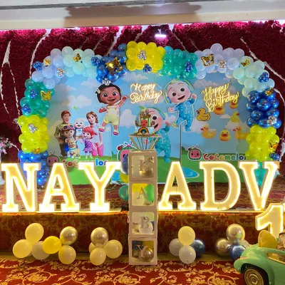 A colorful Cocomelon birthday party featuring a full balloon arch, a themed backdrop with all the characters, and large, light-up letters spelling out the birthday boy's name.