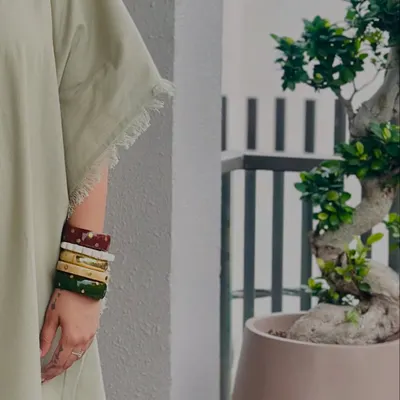 Here is a close-up of my handmade wooden bangles. I love stacking different colors and finishes to create a personalized look. They add an earthy, artisanal touch to any outfit, like this simple green kaftan.