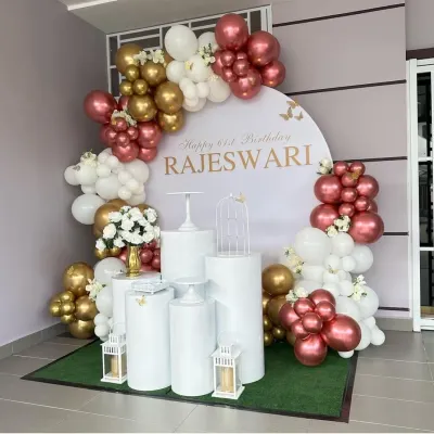 An elegant 61st birthday for Rajeswari with a personalized round backdrop. The decor features a sophisticated color palette of rose gold, white, and gold, with clean white plinths and lanterns.