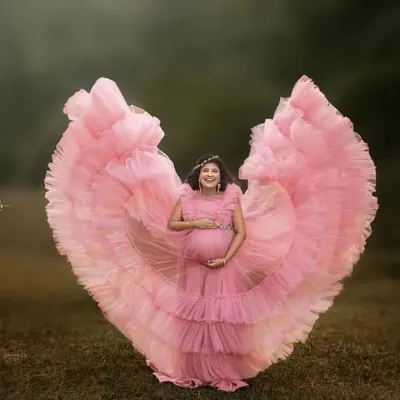 The butterfly effect in full bloom. This stunning pink ruffled gown creates a heart shape, beautifully framing the mom-to-be. It's a whimsical and joyful choice for an outdoor maternity session.