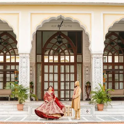 Together, they built a life they loved. This wide shot captures the couple in front of a majestic palace, the bride's twirl adding a touch of joyful movement to a grand and royal portrait.